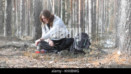 A man in a campaign drinks tea. A young traveler in the woods ca Stock Photo