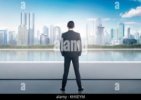 Portrait of asian businessman looking at urban scene from building rooftop
