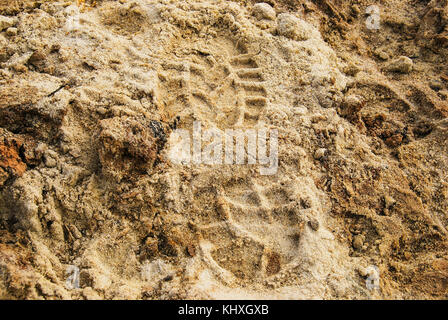Imprint of a man's foot in shoes on wet sand Stock Photo