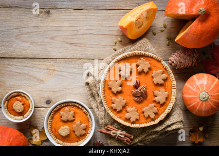 Homemade pumpkin pies with pecan nuts and gingerbread cookies decoration on old wooden table. Top view and copy space for your text Stock Photo
