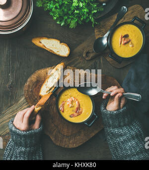 Woman in sweater eating corn creamy soup with shrimps Stock Photo