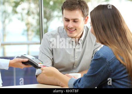 Happy couple paying with credit card in a bar interior Stock Photo