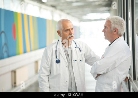 two senior doctors talking in hospotal corridor Stock Photo