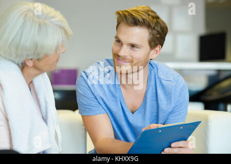 miling male trainer with clipboard and senior in the gym Stock Photo