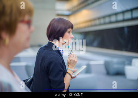 Woman holding smartphone and reading glasses Stock Photo
