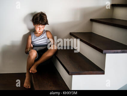 Boy sitting on stairway staring at digital tablet Stock Photo