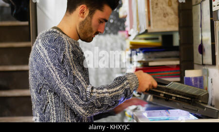 Side view of man working as photocopier and copying papers with machine. Stock Photo
