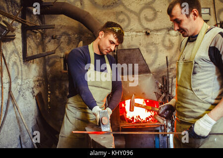 two forge are in working clothes in the forge Stock Photo