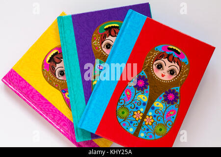 Three different coloured note books with matryoshka doll on cover set on white background Stock Photo