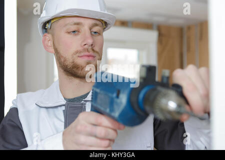 young man using power drill on wall Stock Photo