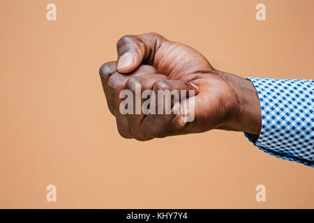 Male black fist isolated on brown background. African american clenched hand, gesturing up Stock Photo