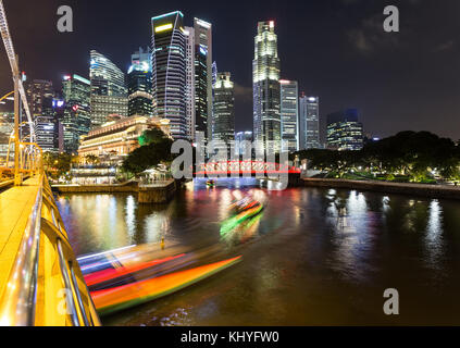 Light trails of tour boat on the Singapore river with the skyscraper of the financial district at night in Singapore in Southeast Asia Stock Photo