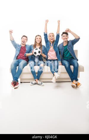 friends with soccer ball sitting on sofa Stock Photo