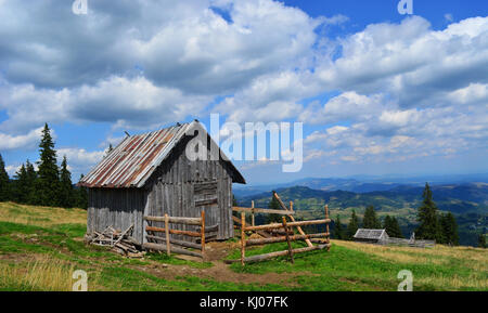 Small cabin located on the top of the hill with the view of the mountains and forest.