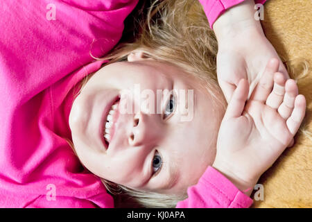 Cute smiling girl with blond hair in pink Stock Photo