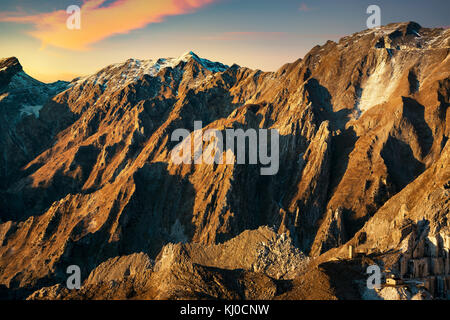 Apuane alpi or Apuan alps snowy mountains and marble quarry at sunset in winter. Carrara, Tuscany, Italy. Stock Photo
