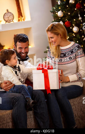 Parents giving Christmas surprise in box to their son Stock Photo