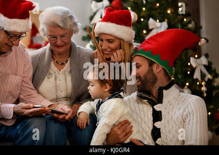 Family on Christmas eve looking Christmas photos on cell phone Stock Photo