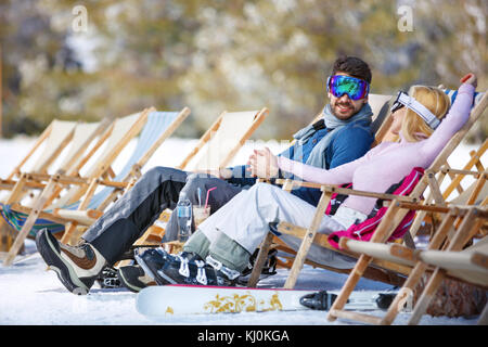 Couple in love enjoy in sun loungers on ski terrain Stock Photo