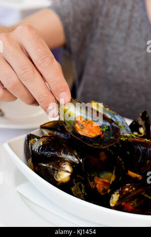 closeup of a young man eatign some mejillones a la marinera, spanish mussels in marinara sauce Stock Photo