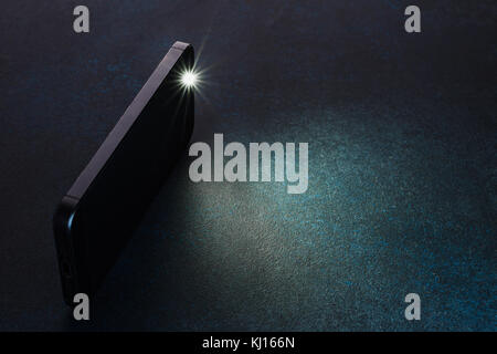 Lantern smartphone shines on a dark background. Stock Photo