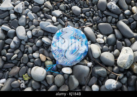 30th,Birthday,balloon,deflated,pollute,beach,found,on,pebbles,Ynyslas Beach,near Borth,north,of,Aberystwyth,Ceredigion,Mid,West,Wales,UK,U.K.,Europe, Stock Photo