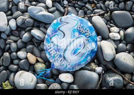 30th,Birthday,balloon,deflated,pollute,beach,found,on,pebbles,Ynyslas Beach,near Borth,north,of,Aberystwyth,Ceredigion,Mid,West,Wales,UK,U.K.,Europe, Stock Photo