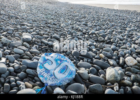 30th,Birthday,balloon,deflated,pollute,beach,found,on,pebbles,Ynyslas Beach,near Borth,north,of,Aberystwyth,Ceredigion,Mid,West,Wales,UK,U.K.,Europe, Stock Photo