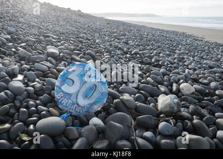 30th,Birthday,balloon,deflated,pollute,beach,found,on,pebbles,Ynyslas Beach,near Borth,north,of,Aberystwyth,Ceredigion,Mid,West,Wales,UK,U.K.,Europe, Stock Photo