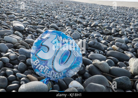 30th,Birthday,balloon,deflated,pollute,beach,found,on,pebbles,Ynyslas Beach,near Borth,north,of,Aberystwyth,Ceredigion,Mid,West,Wales,UK,U.K.,Europe, Stock Photo