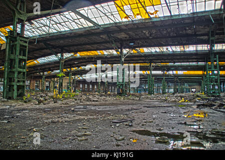 Abandoned old factory hall with windows in roof. Large space in forgotten industrial interior. Stock Photo