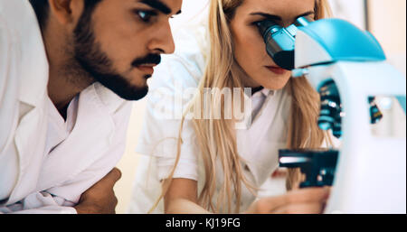 Group of scientists doing research looking through microscope Stock Photo