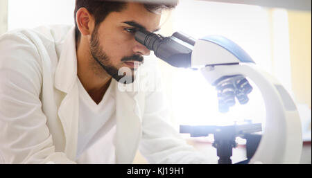 Young scientist looking through microscope in laboratory Stock Photo