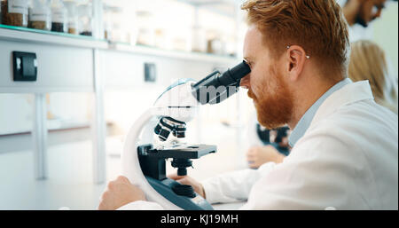 Young scientist looking through microscope in laboratory Stock Photo