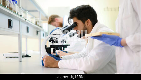 Young scientist looking through microscope in laboratory Stock Photo