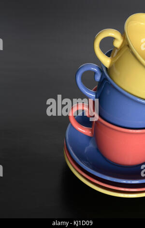 Stack of three motley cups standing on black background with copy space Stock Photo