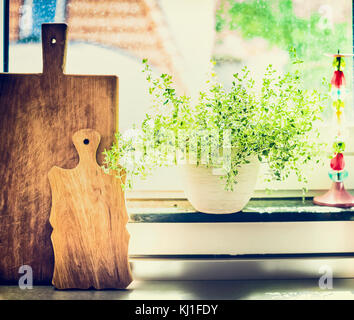 Kitchen cooking herbs in flowers pot on window still with cuting board Stock Photo