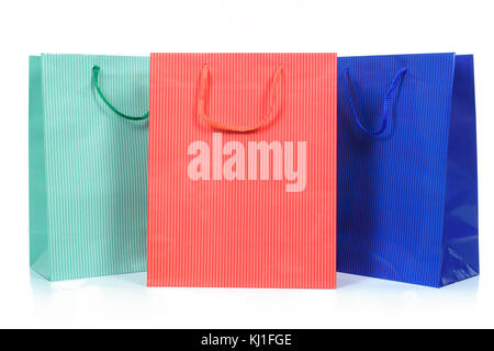 Three shopping bags in different colors in close up and isolated on a white background. Stock Photo