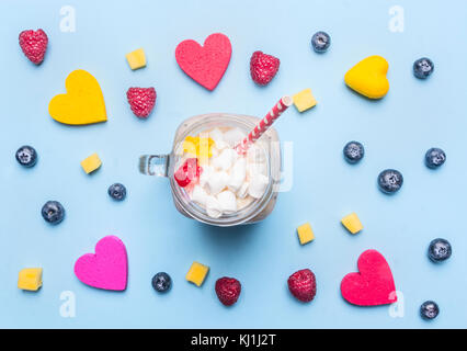 fresh smoothies with raspberry, kiwi and bananas on a blue background, with the expansion of multi-colored hearts around, healthy food, valentines day Stock Photo