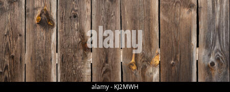 Brown wooden vintage background from old planks. Panoramic striped texture from faded boards with slits and knots. Stock Photo