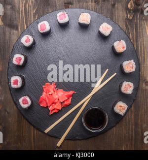 Japanese food, sushi with salmon and tuna, fresh ginger,  soy sauce and chopsticks lined up on a tray of chalk boards, frame, space for text, top view Stock Photo