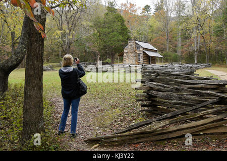Woman photographing the historic John Oliver Cabin in autumn, Cades Cove, Great Smoky Mountains National Park, Tennessee Stock Photo