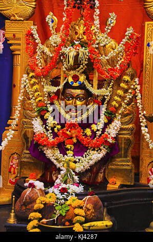 Brass idol of Lord Shiva (only face) and Prabhaval made of brass, decorated with a lot flowers and garlands. Belgavi, Karnataka, India Stock Photo