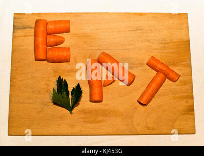 orange carrot on wooden board as a word eat Stock Photo