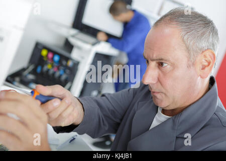 mature male technician checking fridge with digital multimeter at home Stock Photo