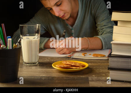 young man in a study table desk with books a open sketch book and pencil bucket, university study, school. Stock Photo