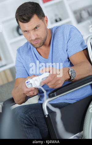 man in wheelchair playing computer game Stock Photo