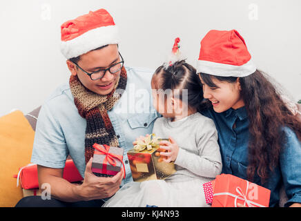 Happy family Asia family wear santa claus hat exchange Christmas gift box at house xmas party,Holiday celebrating festive concept,vintage filter Stock Photo