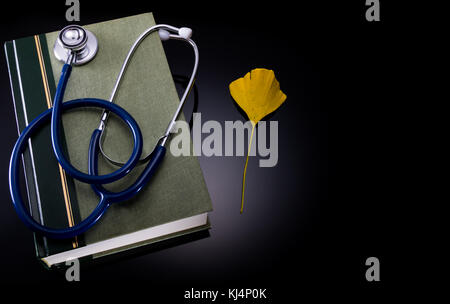 Medical handbook , stethoscope and ginkgo leaf. Stock Photo