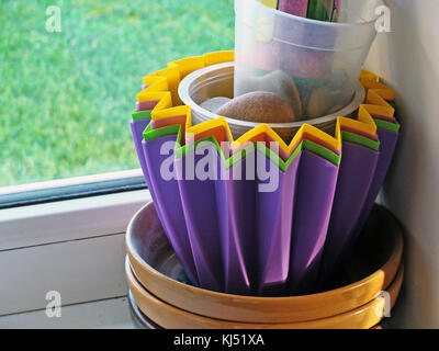Colorful  plastic and ceramic flower pots on window sill close up. Stock Photo